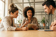 © raquel - Colleagues Discussing Project Using Tablet During Meeting