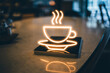© DreamyDesignsCo - Warm neon coffee cup glowing on modern bar countertop