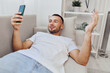 © SHOTPRIME STUDIO - Happy man relaxing on a couch, engaging with his smartphone. Modern home interior with bright colors, capturing the essence of leisure and technology in 2025.