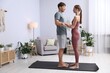 © New Africa - Young woman and man standing on sadhu boards on yoga mat at home