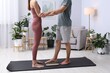 © New Africa - Young woman and man standing on sadhu boards on yoga mat at home, closeup