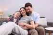 © New Africa - Pregnant woman, her husband and daughter on sofa at home