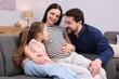 © New Africa - Pregnant woman, her husband and daughter on sofa at home
