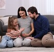 © New Africa - Pregnant woman, her husband and daughter on floor at home