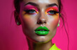 © Pete - Woman wears bright neon eye shadow and green lip gloss. She has blue eyes and dark hair. Her skin glows under studio lights. This is a close-up portrait.