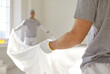 © Studio Romantic - Painters spread plastic sheet indoors for renovation. Workers with gloves pull plastic to cover floors, preparing the bright interior for painting. Concept shows surface protection and prep.