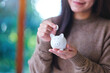 © Farknot Architect - Closeup image of a woman holding and putting coins into piggy bank for saving money concept