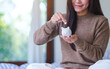 © Farknot Architect - Closeup image of a woman holding and putting coins into piggy bank for saving money concept