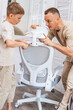 © Aboltin - Home office creation process with father and child assembling chair together. Family teamwork, learning skills, comfortable interior and positive domestic lifestyle concept