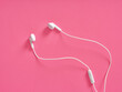 © Cagkan - White wired earbuds resting on pink background