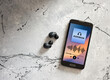 © Cagkan - Smartphone with audiobook app and wireless earbuds on gray background