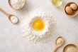 © CreativeLight - Top view of egg yolk centered in flour on light stone surface surrounded by wooden spoons and bowls bright natural light clean baking preparation concept