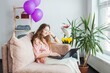 © Tatyana Gladskih - teen girl using laptop while sitting on sofa in living room at home