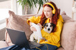 © Tatyana Gladskih - Millennial teen girl sit at couch in living room study on laptop making notes