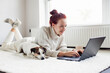 © Tatyana Gladskih - Attractive young Woman with Laptop, happy teen girl with dog Jack Russell lying in white room at home