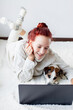 © Tatyana Gladskih - Attractive young Woman with Laptop, happy teen girl with dog lying on white blanket in room at home