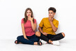 © luismolinero - Young couple sitting on the floor isolated on white background happy and smiling covering mouth with hand