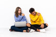 © luismolinero - Young couple with a laptop sitting on the floor isolated on white background suffering from pain in shoulder for having made an effort