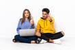 © luismolinero - Young couple with a laptop sitting on the floor isolated on white background doing coming gesture