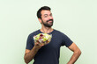 © luismolinero - Young handsome man with salad over isolated green wall smiling