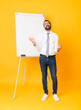 © luismolinero - Full-length shot of businessman giving a presentation on white board over isolated yellow background smiling a lot