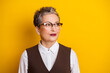 © deagreez - Confident mature businesswoman with short grey hair in a white shirt and brown vest against a yellow background