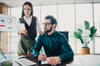 © deagreez - Business colleagues collaborate in a modern office as one writes notes and the other reviews charts on a screen