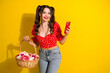 © deagreez - Young glamorous woman with red top and basket of flowers posing with smartphone against yellow background