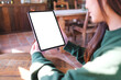© Farknot Architect - Mockup image of a woman holding digital tablet with blank white desktop screen in cafe