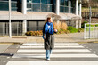 © Iryna - Woman walks across a street in a city on a sunny day near a modern building