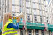 © Iryna - Woman builder manages construction site using megaphone to direct workers
