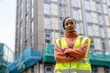 © Iryna - Woman builder in safety jacket stands confidently on construction site with buildings in progress