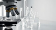 © Anzhelika - Close up of a microscope in a laboratory, with various glass flasks in background. Concept of scientific research, education, and medical analysis.