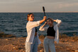 © svetograph - Women Selfie Sunset Beach: Two women taking a selfie with a selfie stick while standing on a beach at sunset.