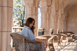 © svetograph - Woman, Patio, Chair - A woman sits on a wicker chair on a patio with a view of a building and trees.