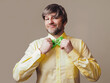 © mark_gusev - Man in yellow shirt fixing Irish green bow tie with Irish shamrock, male in his 40s or 50s with short grey beard and happy face. Stylish gentlemen. Light color background.