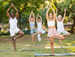 © JackF - Smiling fit young girl practicing hatha yoga at group session in serene environment of green summer park, doing Vrikshasana asana balancing on one leg