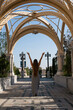 © svetograph - Woman Arches Crosses Religious Landmark - Woman raising her arms in a celebratory pose, standing in a pathway surrounded by intricately designed arches, crosses, and other religious symbols.
