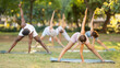 © JackF - During street workout, yoga practice on lawn in public park, multinational athletes of different ages fulfil carry out Prasarita Padottanasana exercise. Students attend outdoor yoga lesson in park