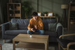 © Miljan Živković - Teenager sitting on sofa holding remote control looking bored