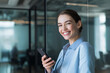 © Photoenthusiast82 - Portrait of happy businesswoman with a smartphone in office looking at camera