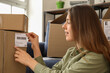 © Pixel-Shot - Young woman packing parcel for client at home, closeup