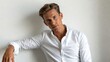© mila103 - Young caucasian male in white shirt with thoughtful expression against plain background.