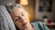 © BornHappy - An elderly woman with her hair in a bun sleeping soundly against a textured grey cushion in a warm interior