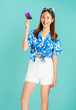 © sitthiphong - Happy fun young Asian woman wearing floral shirt with plastic glasses and holding credit card on blue background