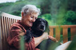 © Halfpoint - Older woman with dog sitting on terrace.