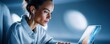 © Yevheniiya - A focused woman types on a laptop while wearing earphones in a dimly lit setting.