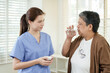 © Ekkasit A Siam - Asian female physiotherapist assisting senior asian woman in drinking water after taking medicine during homecare session highlighting care connection and professional elderly support