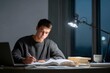 © Anna Lurye - Teenage boy studying mathematics at a desk late at night under a lamp representing academic dedication focus and exam preparation in a home environment