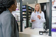 © zinkevych - African american young woman paying at the cashier desk at the pharmacy
